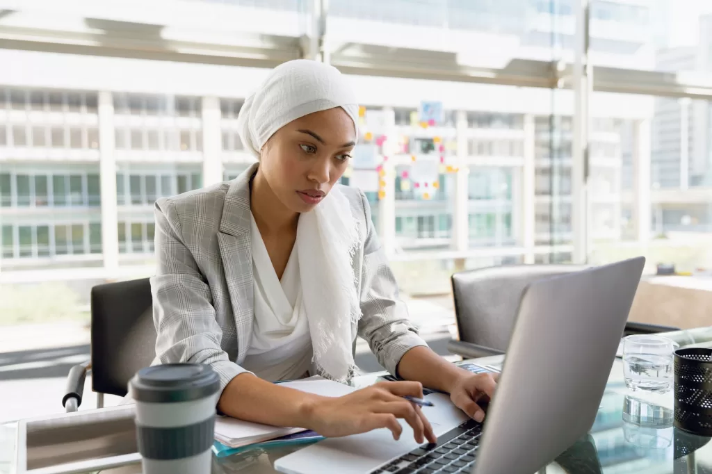 Maui Website Design - Businesswoman in hijab working on laptop at desk in a modern office